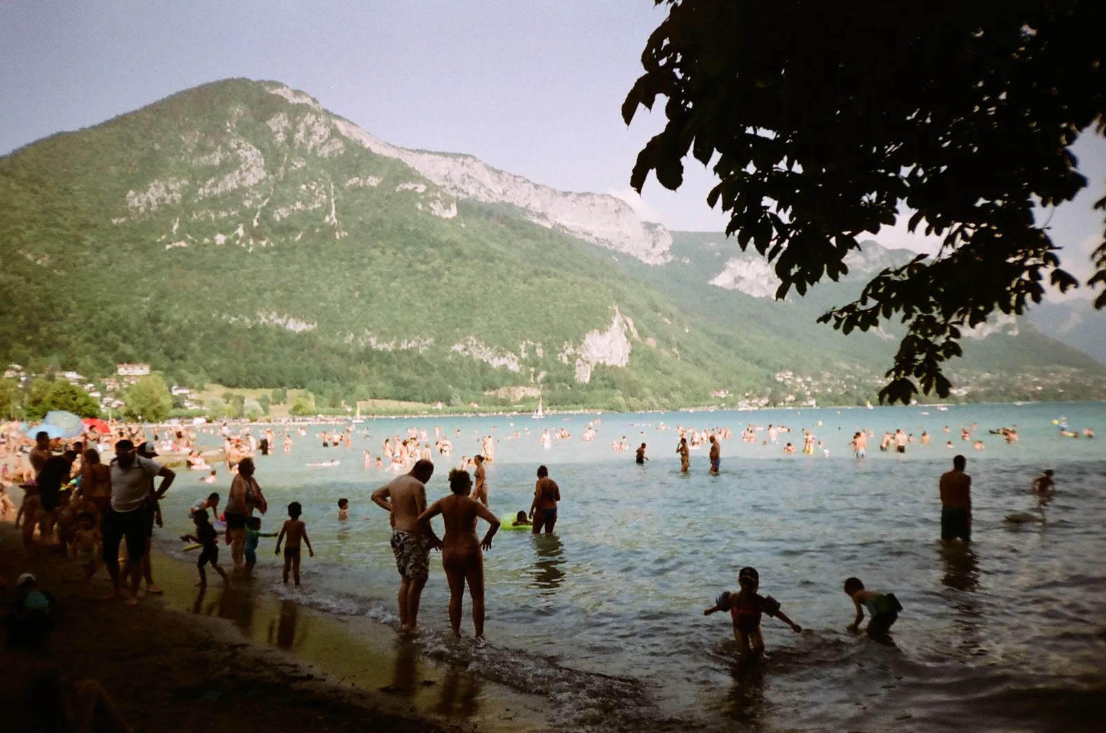 Baigneurs sur la rive d'un lac alpin, montagne en arrière-plan (lac d'Annecy)