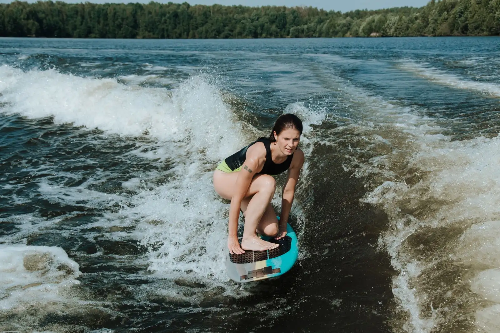 Pratiquante de wakesurf accroupie sur sa planche dans la vague d'un bateau