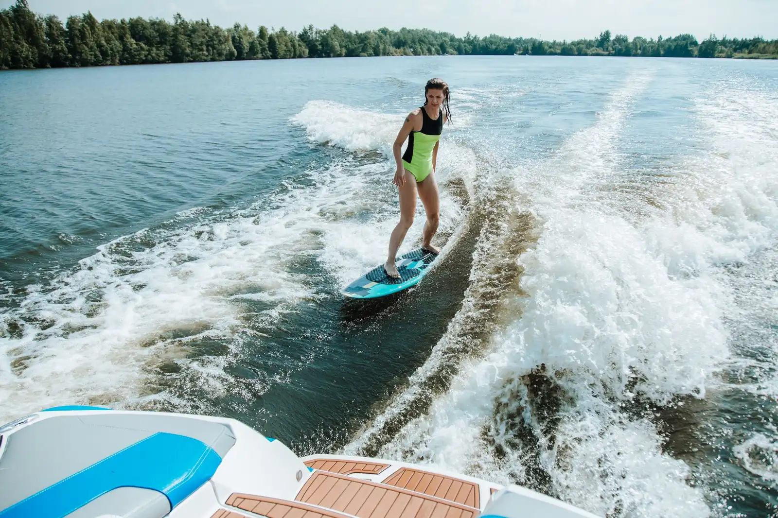 Femme debout sur une planche de wakesurf dans le sillage d'un bateau sur un lac