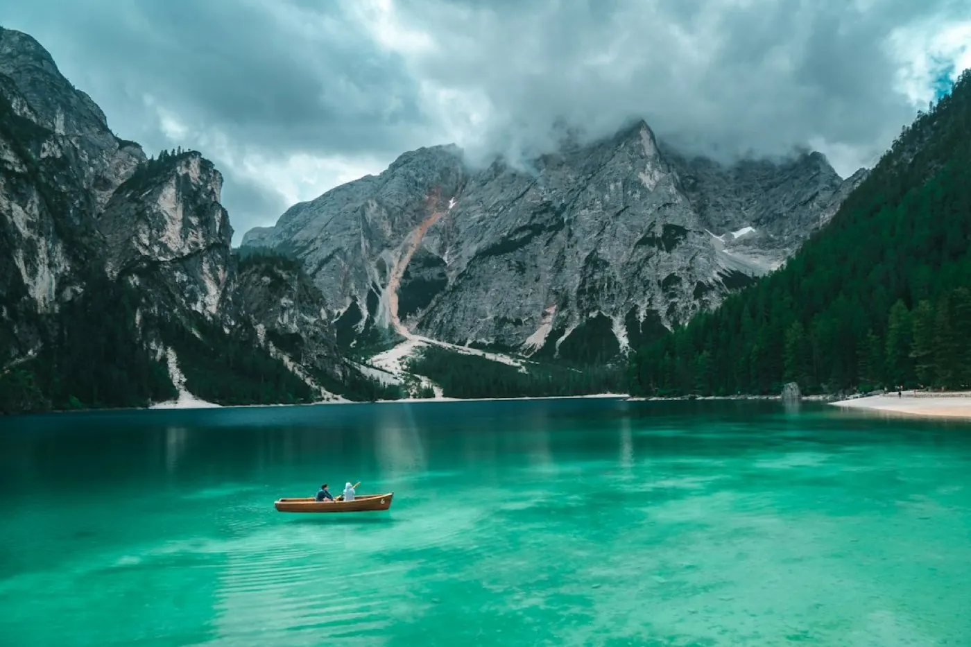 Barque en bois sur un lac turquoise au pied des montagnes