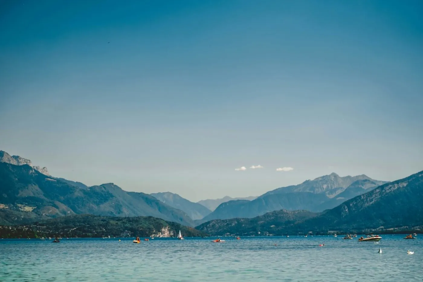 Lac de montagne en été avec voiliers et bateaux à moteur au loin