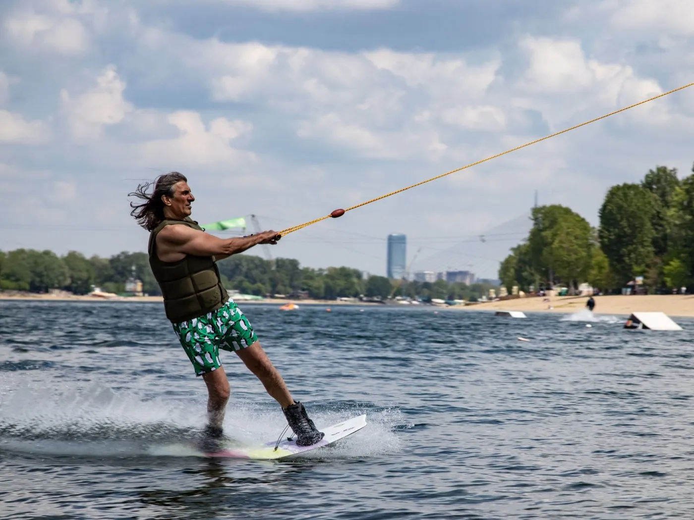Wakeboardeur tracté par un câble sur un plan d'eau, lors d'une séance d'école de wakeboard