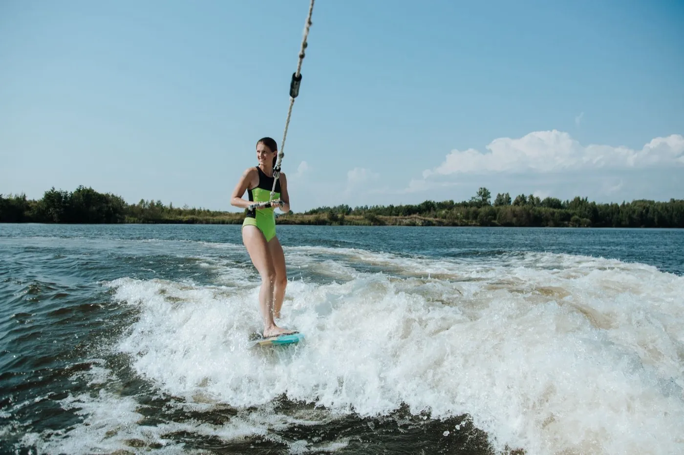 Jeune femme en wakesurf dans le sillage d'un bateau sur un lac
