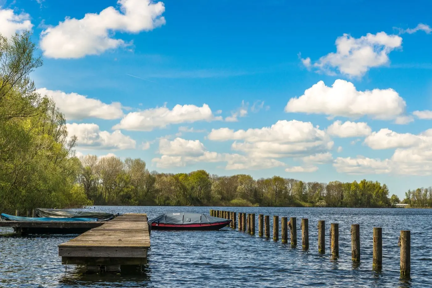 Ponton en bois et bateau bâché amarré sur un lac