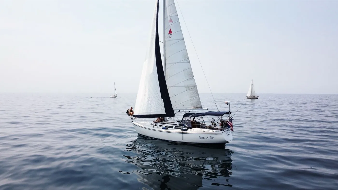 Voilier naviguant sous voiles sur une eau calme, équipage à bord