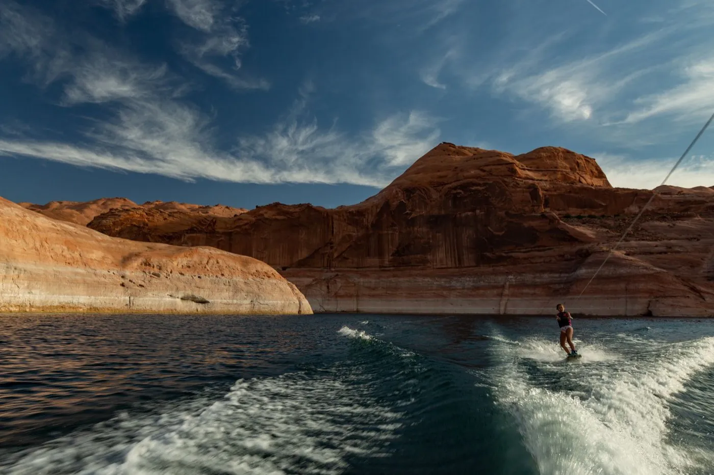 Wakesurfeuse dans le sillage d'un bateau au pied de falaises rouges